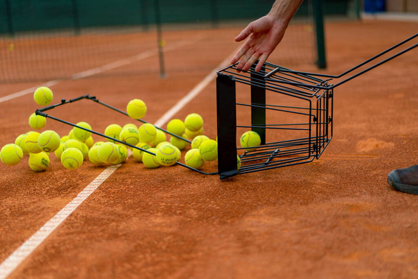 крупним планом багато тенісних м'ячів, що випадають з кошика глини тенісний корт спортивних змагань тренувань - Фото, зображення