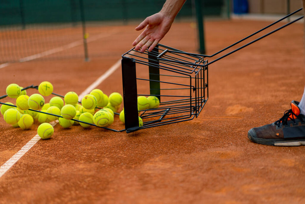 close-up van vele tennisballen vallen uit mand klei tennisbaan sport wedstrijd training - Foto, afbeelding