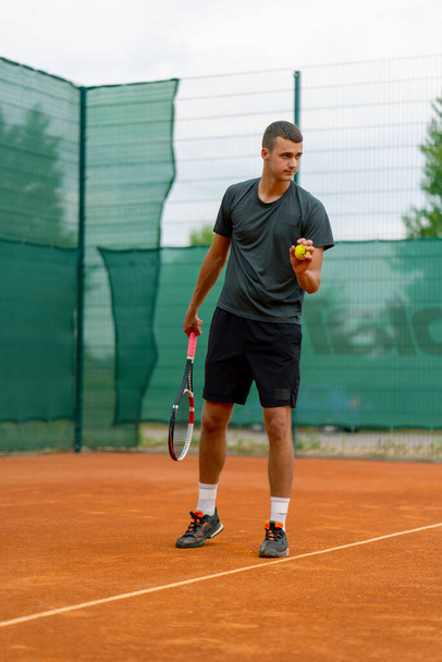 joven entrenador jugador profesional en las prácticas de tenis al aire libre golpes con raqueta pelota de tenis - Foto, imagen