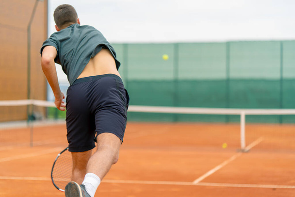 屋外テニスコートの若いプロ選手コーチは,ラケットテニスボールでストロークを実践します - 写真・画像