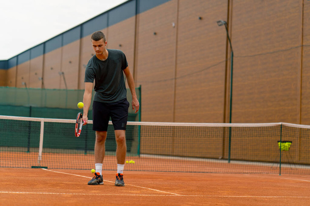 νεαρός προπονητής τενίστας χτυπάει την μπάλα με ρακέτα στο γήπεδο του τένις προετοιμασία για τον αθλητισμό του ανταγωνισμού τρόπο ζωής - Φωτογραφία, εικόνα