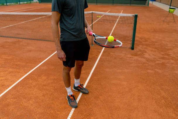 крупним планом молодий тенісист, який бив м'яч з ракеткою на тенісному корті, готуючись до змагань спортивного способу життя - Фото, зображення