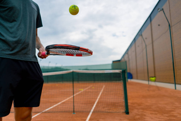 Genç tenis oyuncusu antrenörü tenis kortunda raketle topa vuruyor ve spor yaşam tarzı yarışmasına hazırlanıyor. - Fotoğraf, Görsel