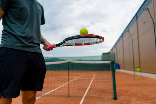 close-up jonge tennisspeler trainer slaan van de bal met een racket op de tennisbaan voor te bereiden op de concurrentie sport levensstijl - Foto, afbeelding