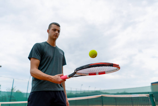若いテニス選手コーチは競技スポーツライフスタイルのために準備テニスコートにラケットでボールを打つ - 写真・画像