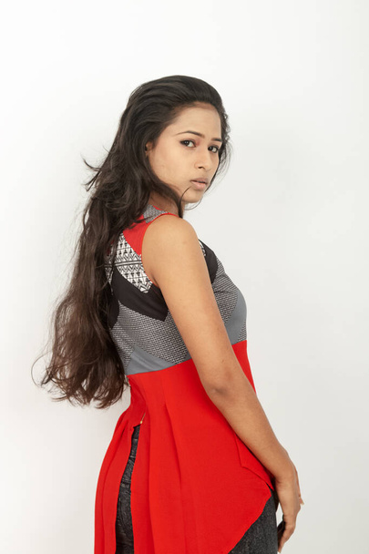 Студійний знімок молодої, красивої індійської жіночої моделі в повсякденному одязі в червоному та сірому дизайнерському верхньому та чорному джинсах на білому тлі. Жіноча модель. Портрет моди. - Фото, зображення