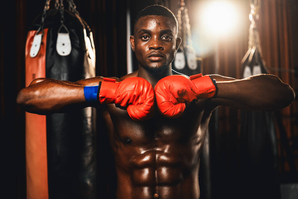 ボクシングファイターのポーズ、アフリカ系アメリカ人ブラックボクサーは積極的な姿勢で一緒に手袋を着用し、キックバッグやボクシング機器とジムで戦う準備ができて手や拳を置きます。インペトゥス - 写真・画像