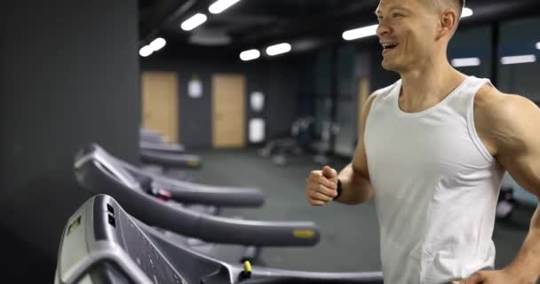 Gezonde sporter loopt op loopband in de fitnessruimte. Man die sport doet op een hardloopmachine in een sportclub - Video