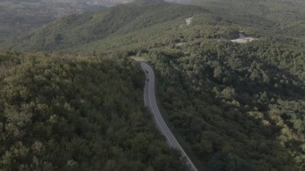 luchtfoto drone beelden van een bochtige asfaltweg op een bergketen tijdens de lente voertuig auto rijden langs de kronkelende weg in Servië omgeven door groen en landschappen vervoer en reizen concept - Video