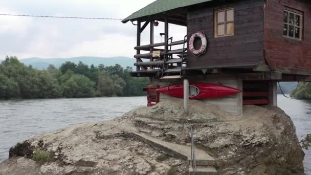 Klein vissershuisje op een rots aan de rivier de Drina in Bajina Basta, Servië. Luchtfoto. Zomer.  - Video