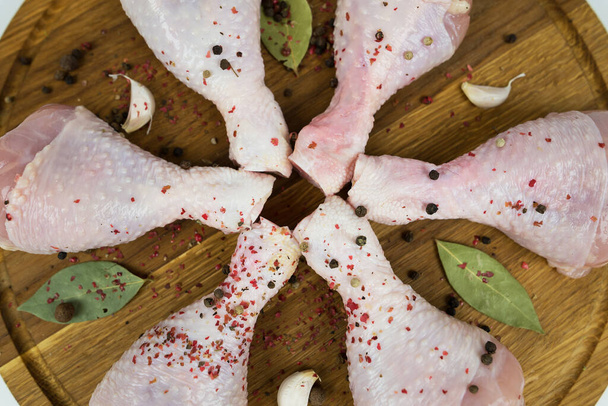 rauwe kippenpoten of drumstokken met specerijen op een houten snijplank. Close-up. - Foto, afbeelding