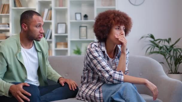 Two biracial lovers clarifying relationships while sitting on couch. Fiery man yelling at woman and gesturing hands in order to evoke any emotions. Offended wife ignoring husband and silently crying. - Footage, Video
