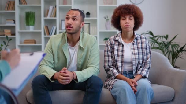 A multikulturális házaspár pszichológushoz megy, hogy megoldja a családi problémákat. Fiatal férfi megosztja saját elképzeléseit a problémákról, miközben a nő csendben és idegesen dörzsöli a kezét. Házassági terápia fogalma. - Felvétel, videó