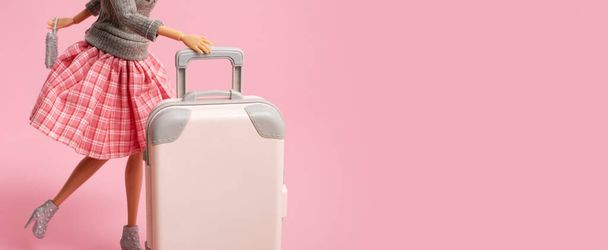 The doll carries a suitcase on wheels. Travel, vacation creative minimalistic concept. Banner with copy space - Photo, Image