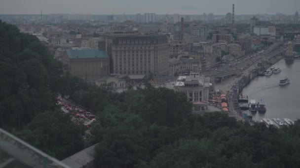 birds eye view of the city, car traffic on the bridge, construction of skyscrapers, people walking along the embankment, where pleasure ships and boats stand and go. gray summer day - Footage, Video