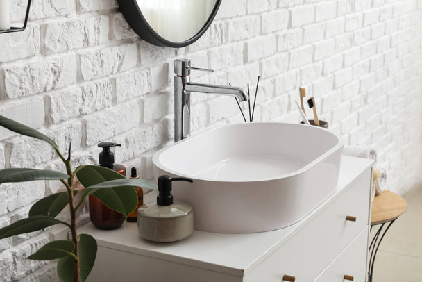 Sink bowl and bath accessories on chest of drawers in bathroom - Photo, Image