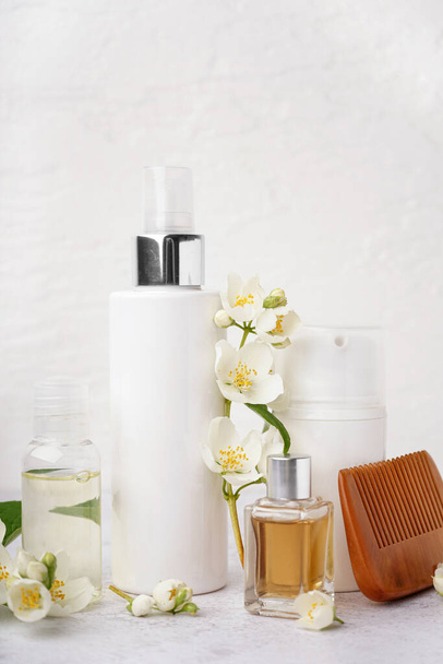 Conjunto de productos cosméticos, peine de pelo y hermosas flores de jazmín sobre fondo claro - Foto, Imagen