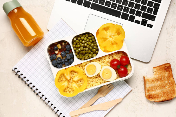 Laptop, flakon gyümölcslé és uzsonnás doboz finom ételekkel fehér alapon - Fotó, kép