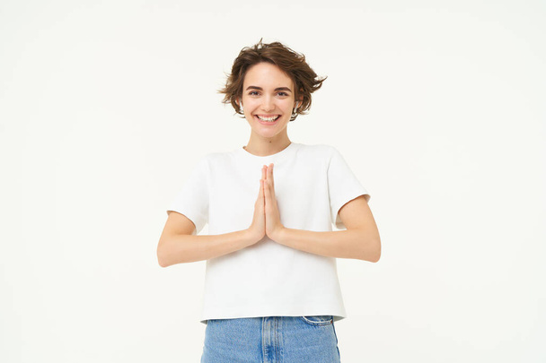 Portrait of brunette young woman holds hands together, namaste gesture, say thank you, grateful, express gratitude and joy, stands over white background. copy space - Photo, Image