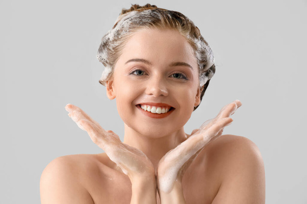 Mladá žena s šamponem na světlém pozadí, detailní záběr - Fotografie, Obrázek