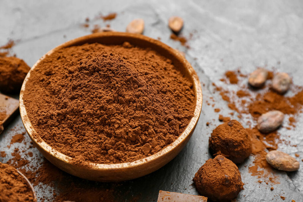 Ciotola con cacao in polvere e caramelle su sfondo nero - Foto, immagini