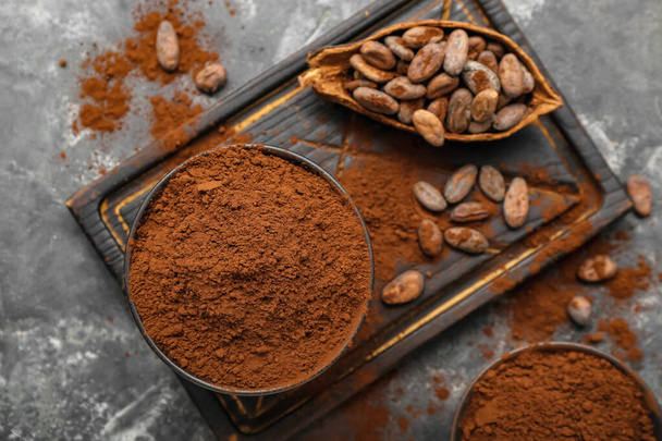 Bowls with cocoa powder and beans on black background - Photo, Image