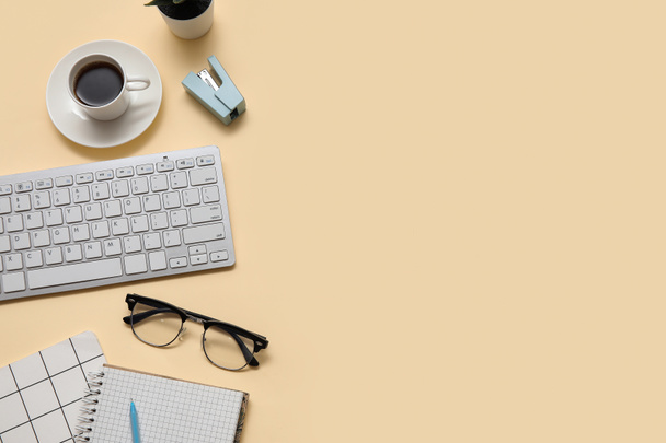 Tastatur, Tasse Kaffee und Schreibwaren auf beigem Hintergrund - Foto, Bild