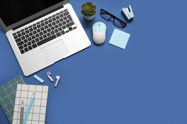 Laptop, computer muis en briefpapier op blauwe achtergrond - Foto, afbeelding