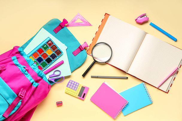Composición con mochila escolar con estilo y diferentes artículos de papelería sobre fondo de color - Foto, Imagen