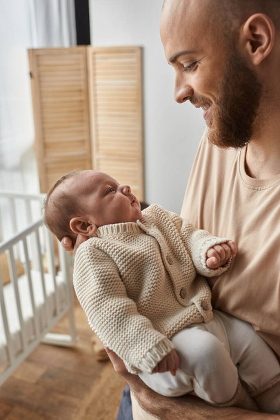 Oh fröhlicher bärtiger Mann, der sein neugeborenes Baby liebevoll ansieht, während er es hält - Foto, Bild