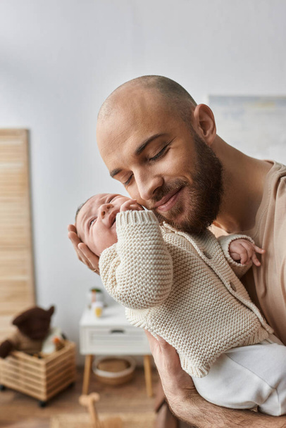 tiro vertical de padre cariñoso barbudo abrazando calurosamente a su bebé recién nacido, concepto de familia - Foto, imagen