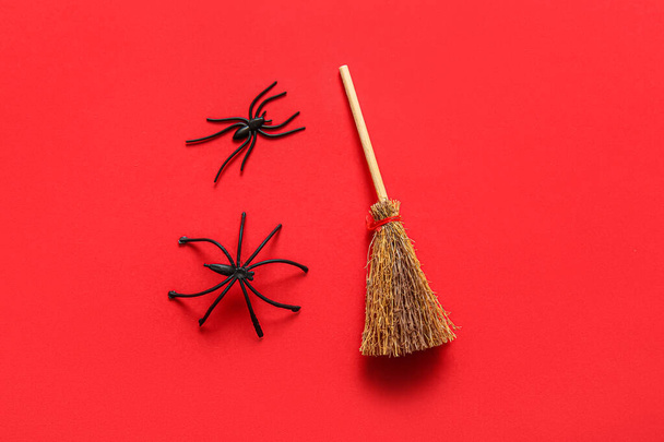Halloween composition with broom and spiders on red background - Photo, Image
