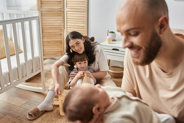 keskittyä äiti leikkii hänen pieni poikansa ja hymyilee hänen hämärtynyt aviomies tilalla vastasyntynyt vauva - Valokuva, kuva