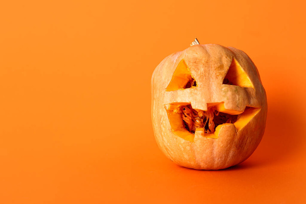 Geschnitzter Kürbis zu Halloween auf orangefarbenem Hintergrund - Foto, Bild