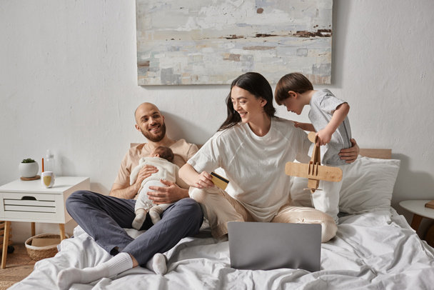 happy beautiful family spending time together in bed with laptop and credit card, modern parenting - Fotografie, Obrázek