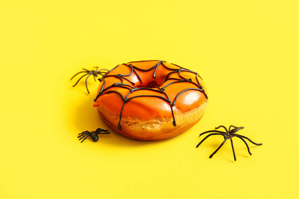 Cadılar Bayramı için lezzetli çörek ve sarı arka planda örümcekler. - Fotoğraf, Görsel