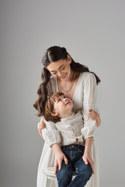 vertical shot joyous mother and her preschool child smiling at each other, family concept - Photo, Image