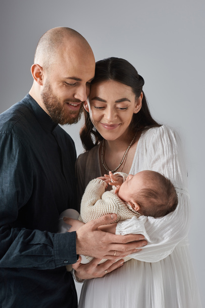 vertical shot of loving young parents holding their newborn baby boy and smiling happily, family - Photo, Image