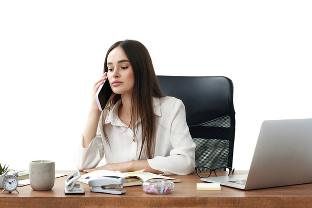 внимательная деловая женщина, работающая с ноутбуком и разговаривающая по телефону с клиентом - Фото, изображение