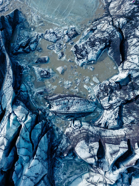 Drone shot of blue glacial rocks on vatnajokull ice mass in iceland, huge icebergs chunks with ice caves creating natural landscape. Breathtaking icy blocks within glacier lagoon. - Photo, Image