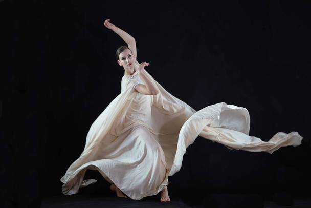 Dancer in a white robe.Beautiful lyrical dancer on a black background.  - Zdjęcie, obraz