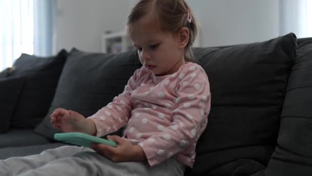 Ένα μικρό παιδί κορίτσι παίζει βιντεοπαιχνίδι στο κινητό τηλέφωνο smartphone - Πλάνα, βίντεο