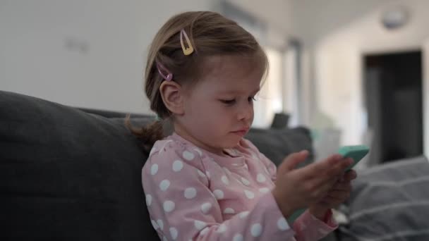 Jedna dziewczynka maluch dziecko grać w grę wideo na smartfonie komórkowym - Materiał filmowy, wideo