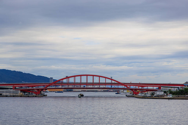 Näkymä vedestä hinaaja ja proomu alla punainen silta Kobe Harbor. Laadukas kuva - Valokuva, kuva