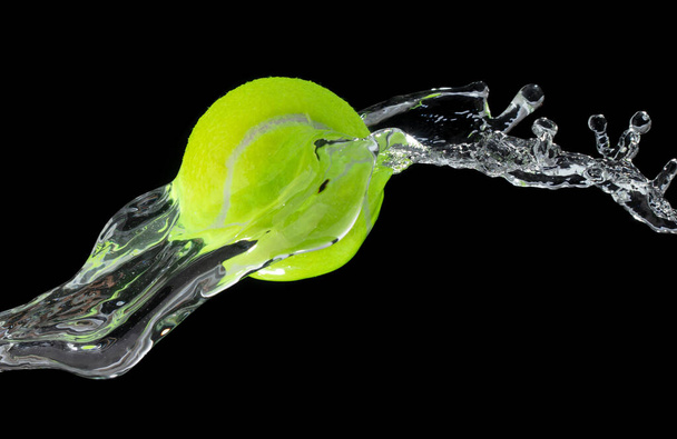 Теннисный мяч попал в воду и брызги в воздухе. Зеленый теннисный мяч летит под дождем и брызги вращения брызг в капельной воде. Черный фон Изолированная серия два изображения - Фото, изображение