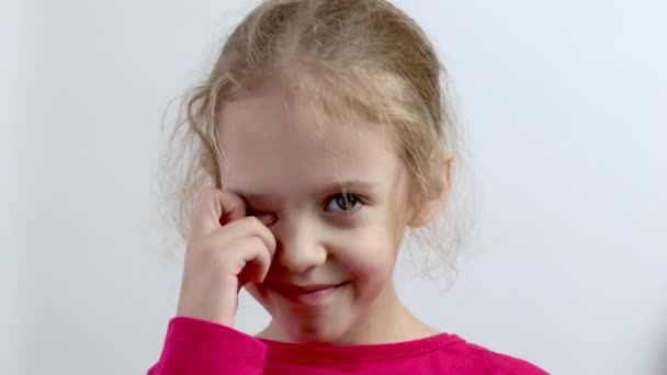 Ένα μικρό κορίτσι χωρίς δόντια χαμογελάει. Κοντινό πλάνο. Μεμονωμένο φόντο. - Πλάνα, βίντεο
