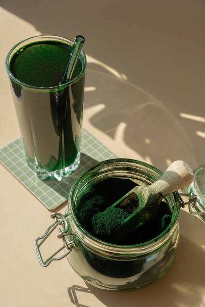 Природные органические зеленые спирулиновые водоросли порошковый напиток на нейтральном бежевом фоне. Вегетарианские коктейли из веганских водорослей хлорелла с добавкой фруктового коктейля и детоксикацией. Инновационный ингредиент - Фото, изображение