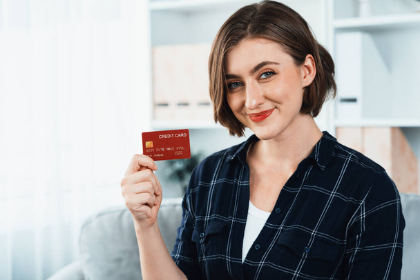 Young happy woman buy product by online shopping at home while ordering items from the internet with credit card online payment system protected by utmost cyber security from online store platform - Photo, Image