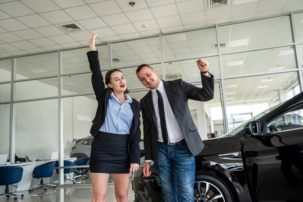 young couple buys a car at a car dealership and is sincerely happy about such a purchase. the concept of buying and selling a car. car dealership - Valokuva, kuva