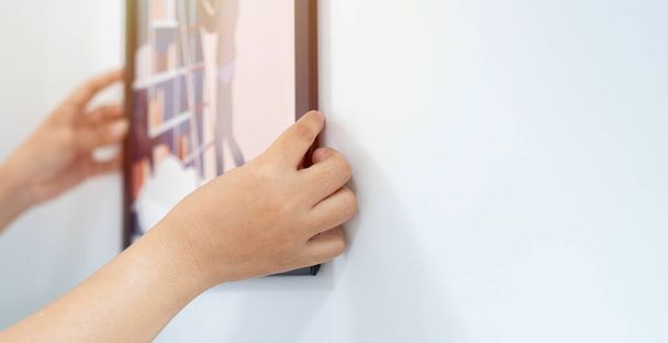 Selektivní zaměření ženských rukou zavěšených na bílou stěnu v novém domě. Mockup, šablona, kopírovací prostor - Fotografie, Obrázek